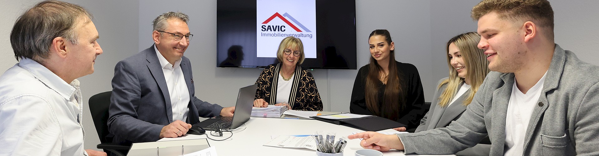 Ein-Team-aus-drei-Maennern-und-drei-Frauen-sitzt-an-einem-Konferenztisch-im-Buero